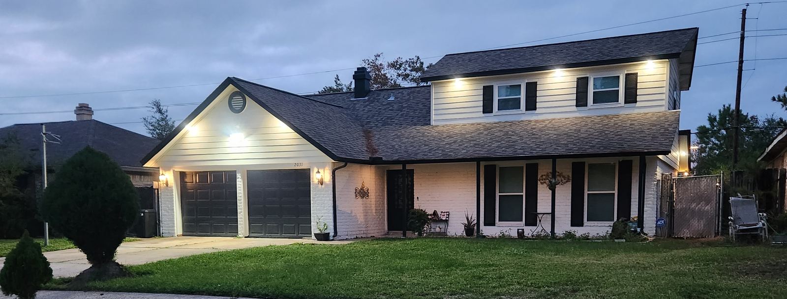 A Houston-area home with the power on at dusk, backed by a standby generator